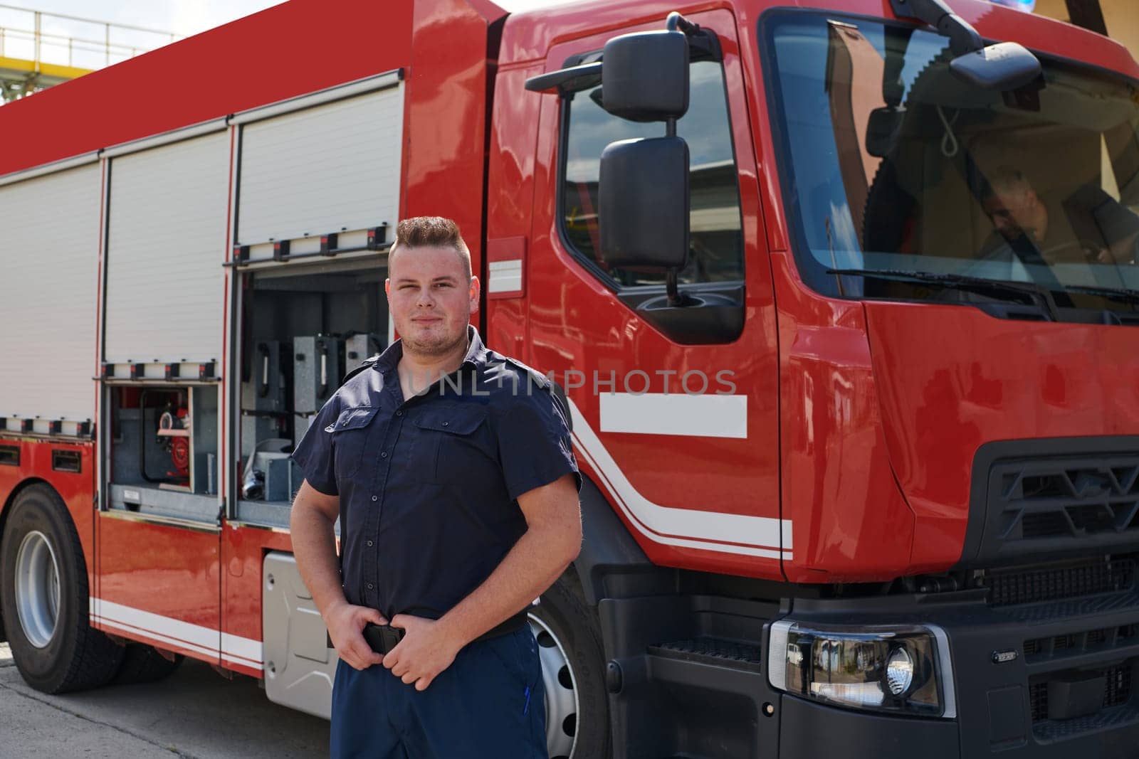 A confident firefighter strikes a pose in front of a modern firetruck, exuding pride, strength, and preparedness for emergency response.