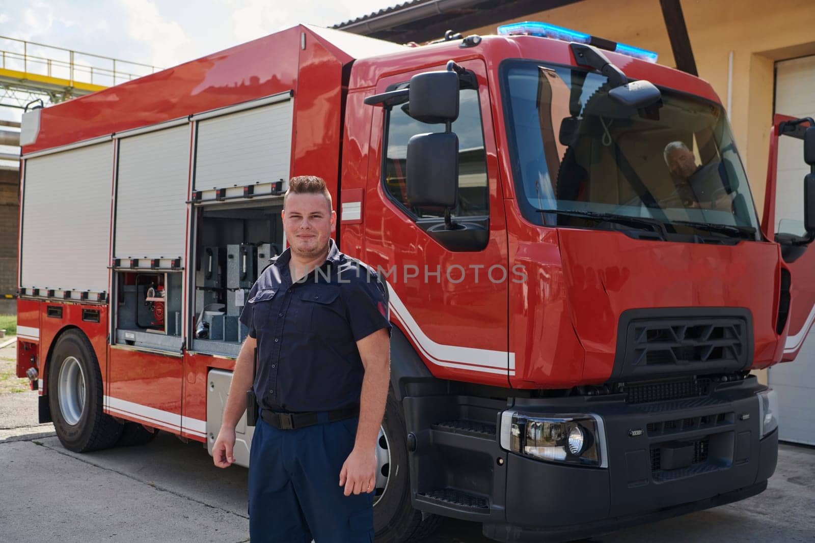 A confident firefighter strikes a pose in front of a modern firetruck, exuding pride, strength, and preparedness for emergency response.