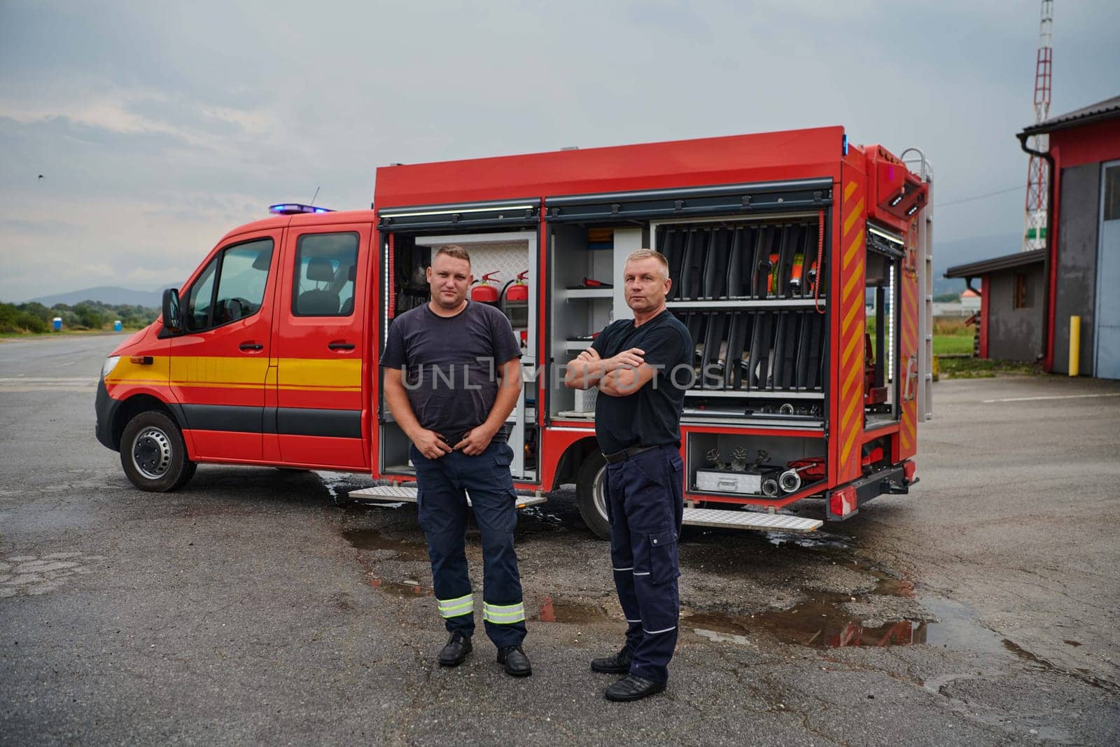 A skilled and dedicated professional firefighting team proudly poses in front of their state of the art firetruck, showcasing their modern equipment and commitment to ensuring public safety. by dotshock