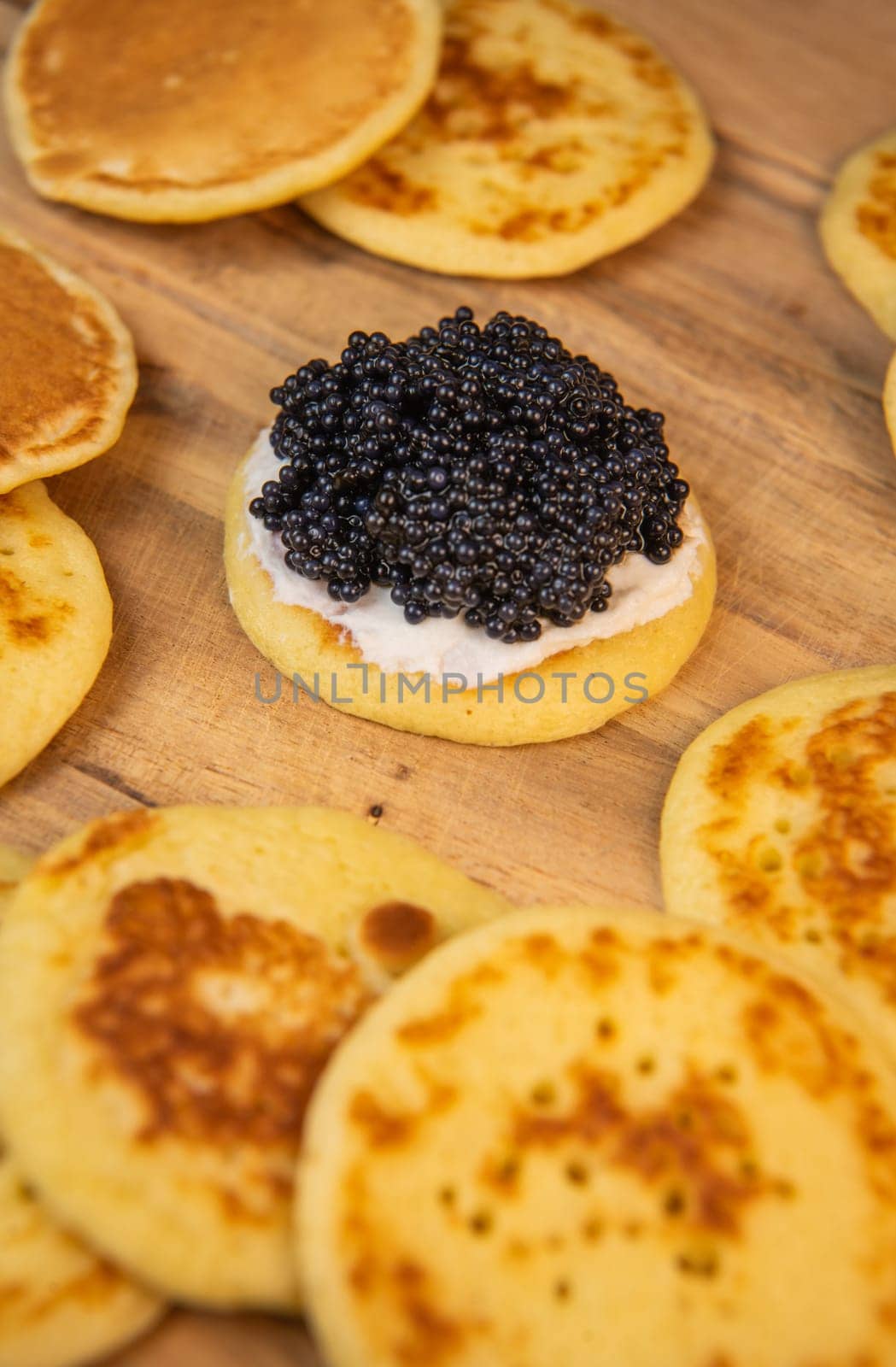 Blinis with black caviar and cream cheese, on a festive dish, mini pancakes, an elegant appetizer by FreeProd