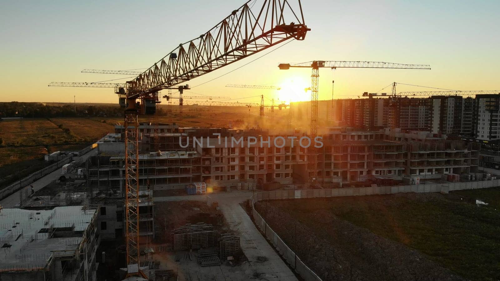 Silhouettes of construction cranes at sunset. Drone video