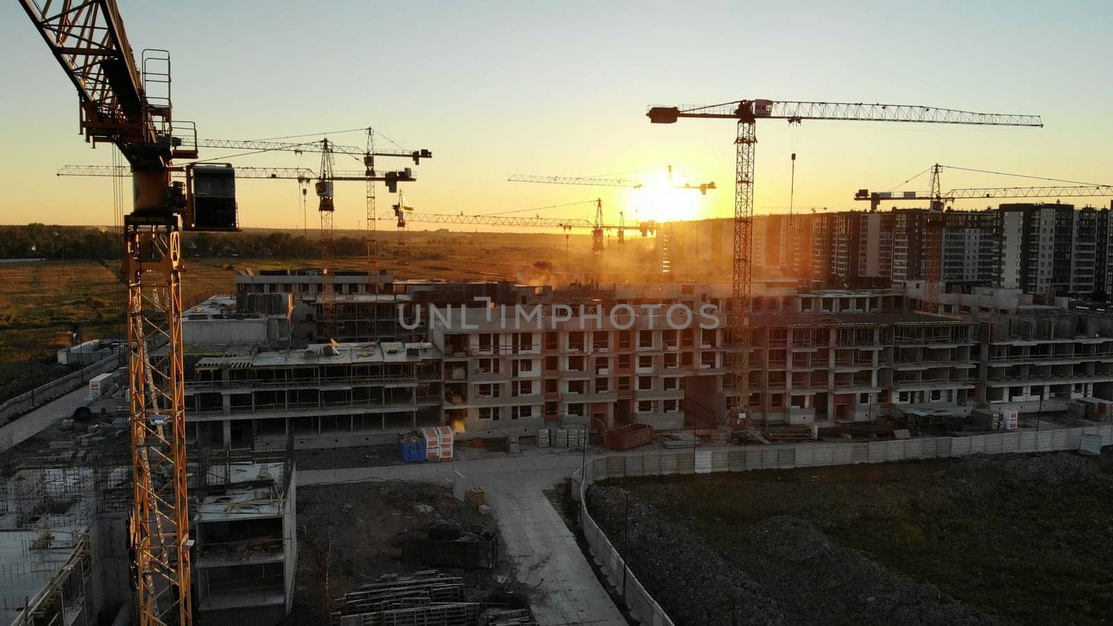 Silhouettes of construction cranes at sunset