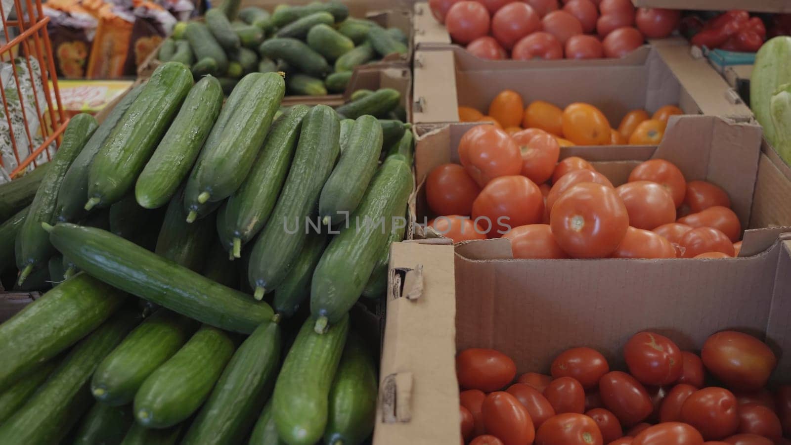 Tomatoes and cucumbers in the boxes of a large store. by DovidPro