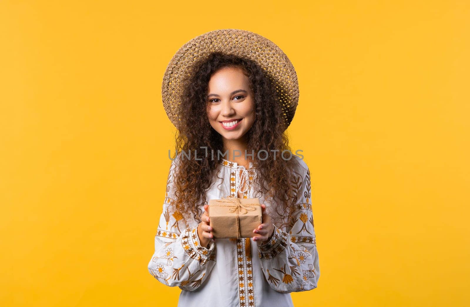 Pretty woman, curly hair with gift box on yellow background. Happy with present. by kristina_kokhanova