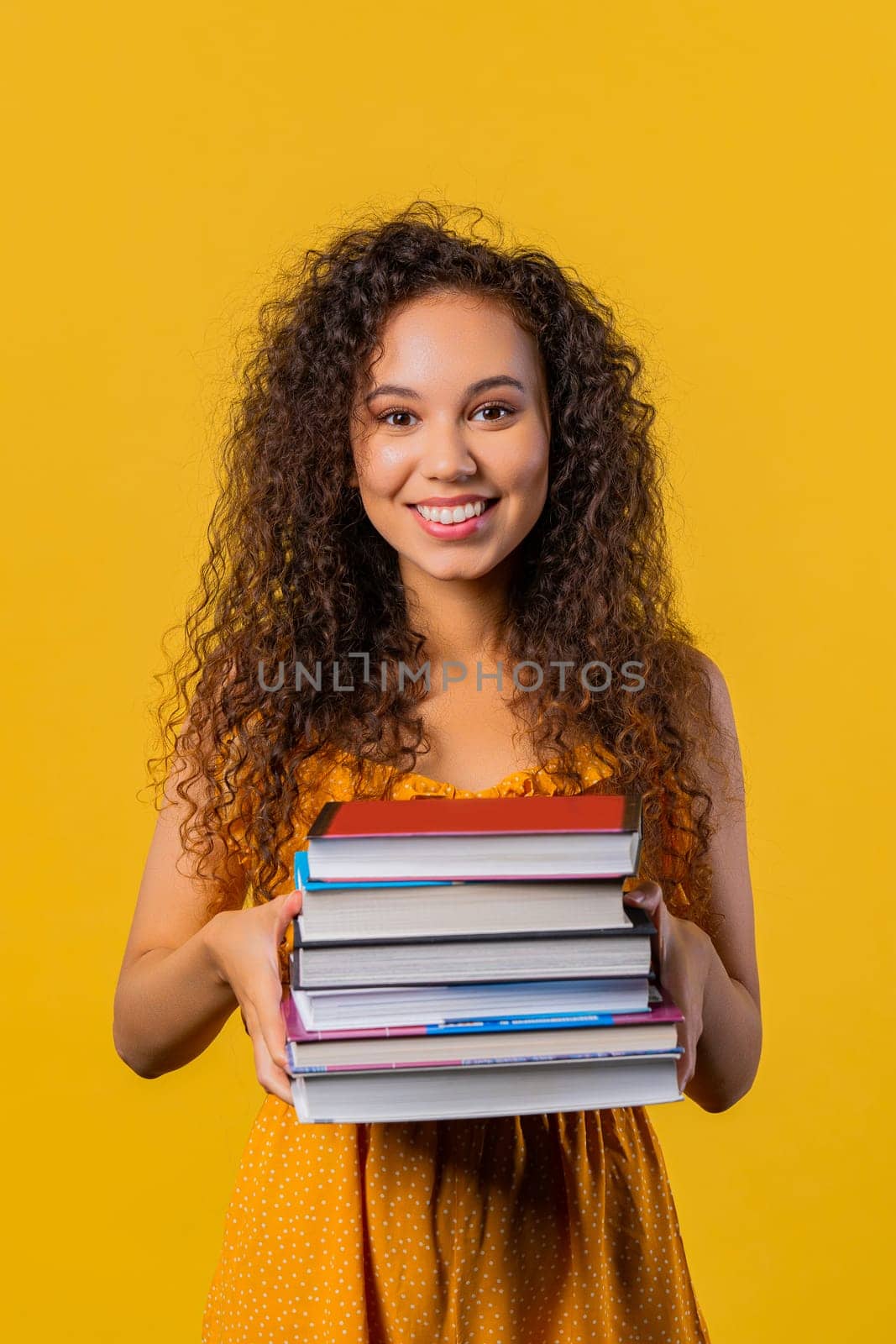 Smiling adult student woman with stack of books from library, yellow background by kristina_kokhanova