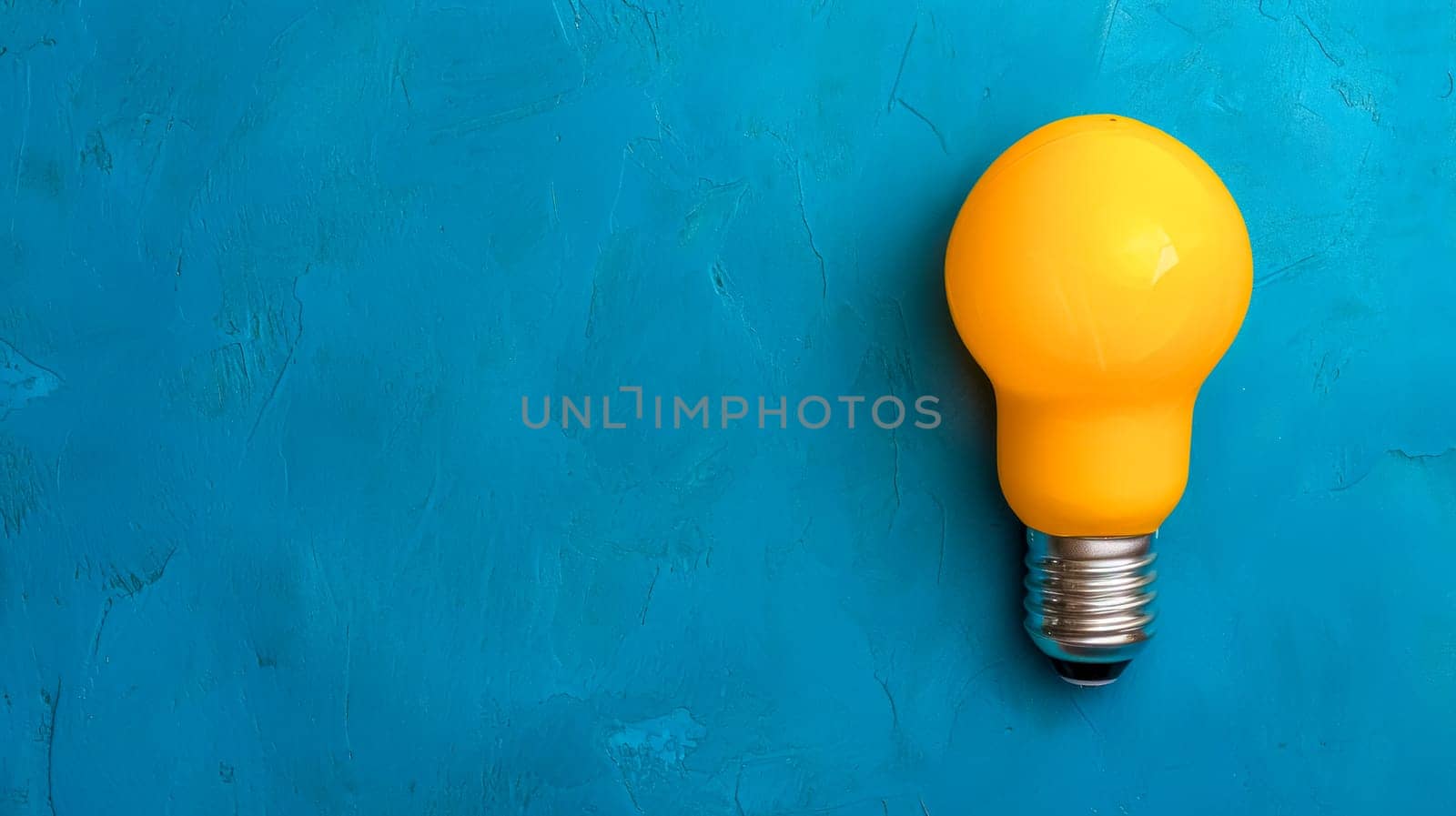 A single bright yellow light bulb against a textured turquoise background, conveying a message of innovation, energy, and creative thinking by Edophoto