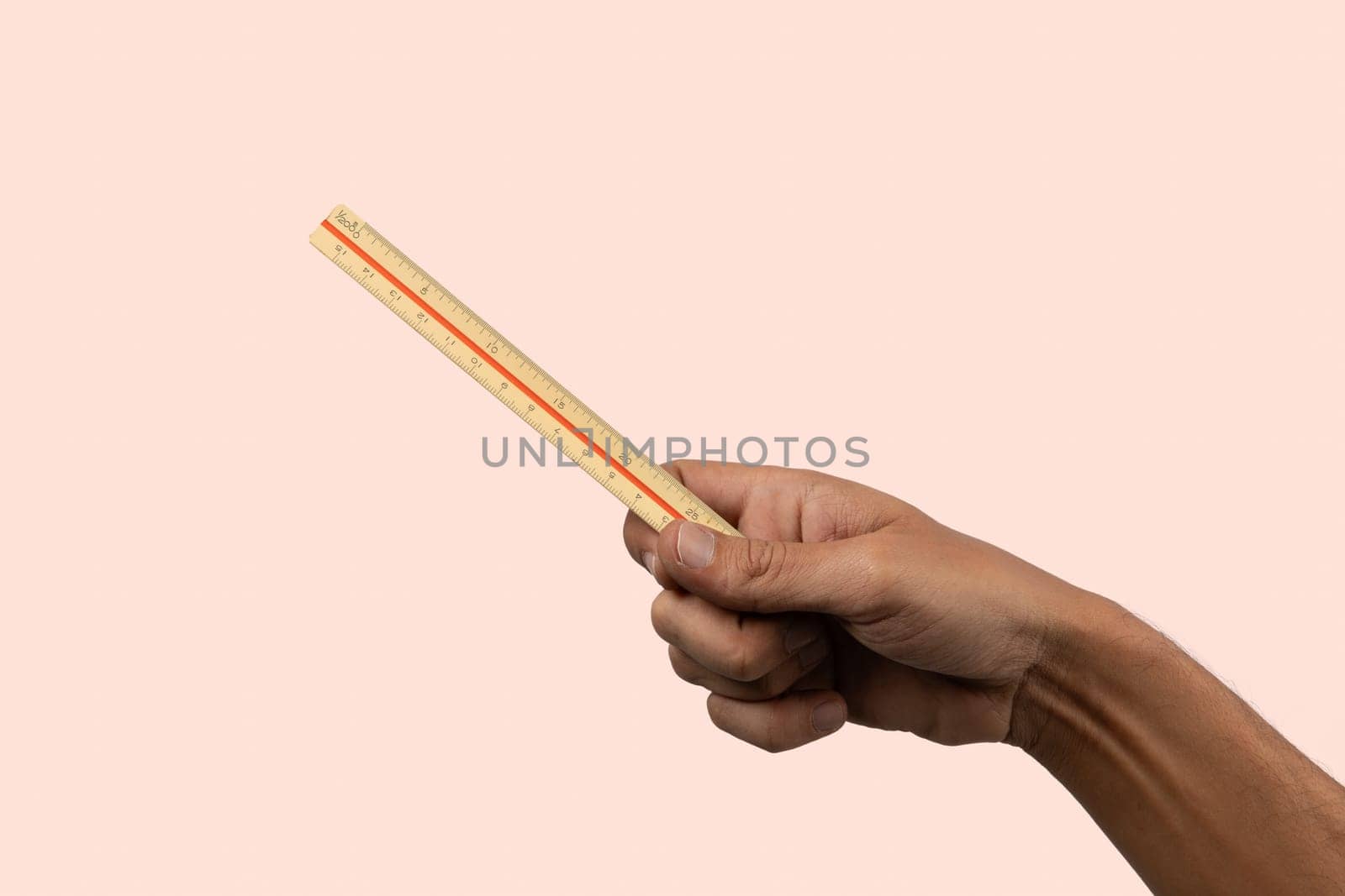 hand holding a ruller on peach background. Education concept. High quality photo