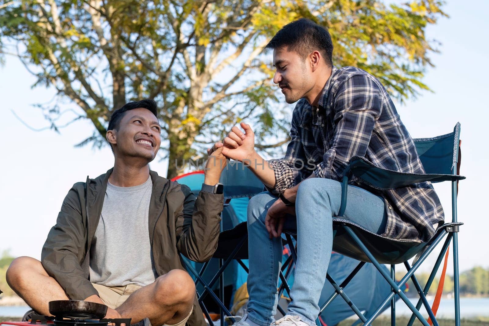 Happy Asian male gay couple on camping together in a forest. romantic vocation trip. lgbt concept by wichayada
