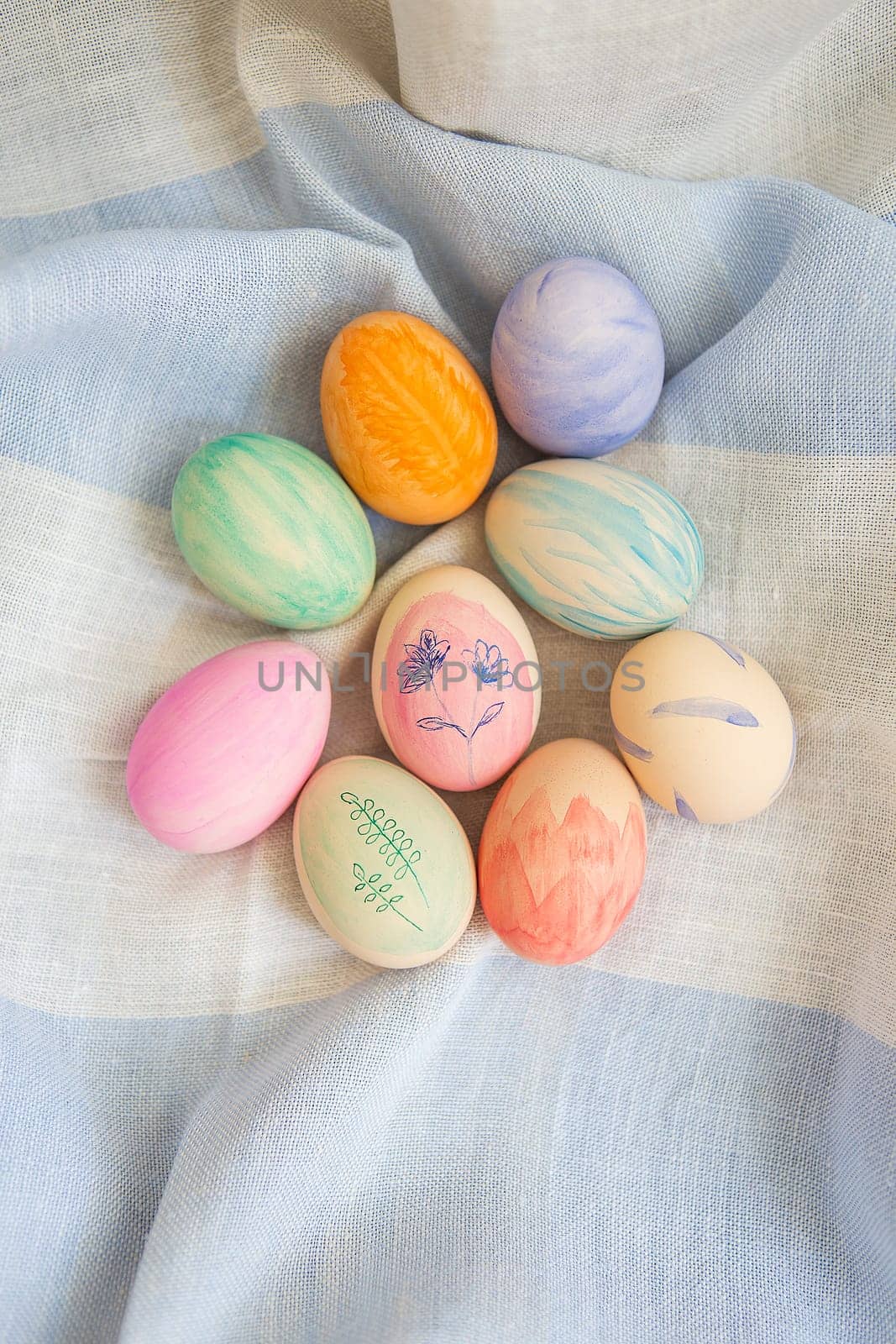 Painted bright and multi-colored Easter eggs on the background of a linen tablecloth, eggs painted with watercolors