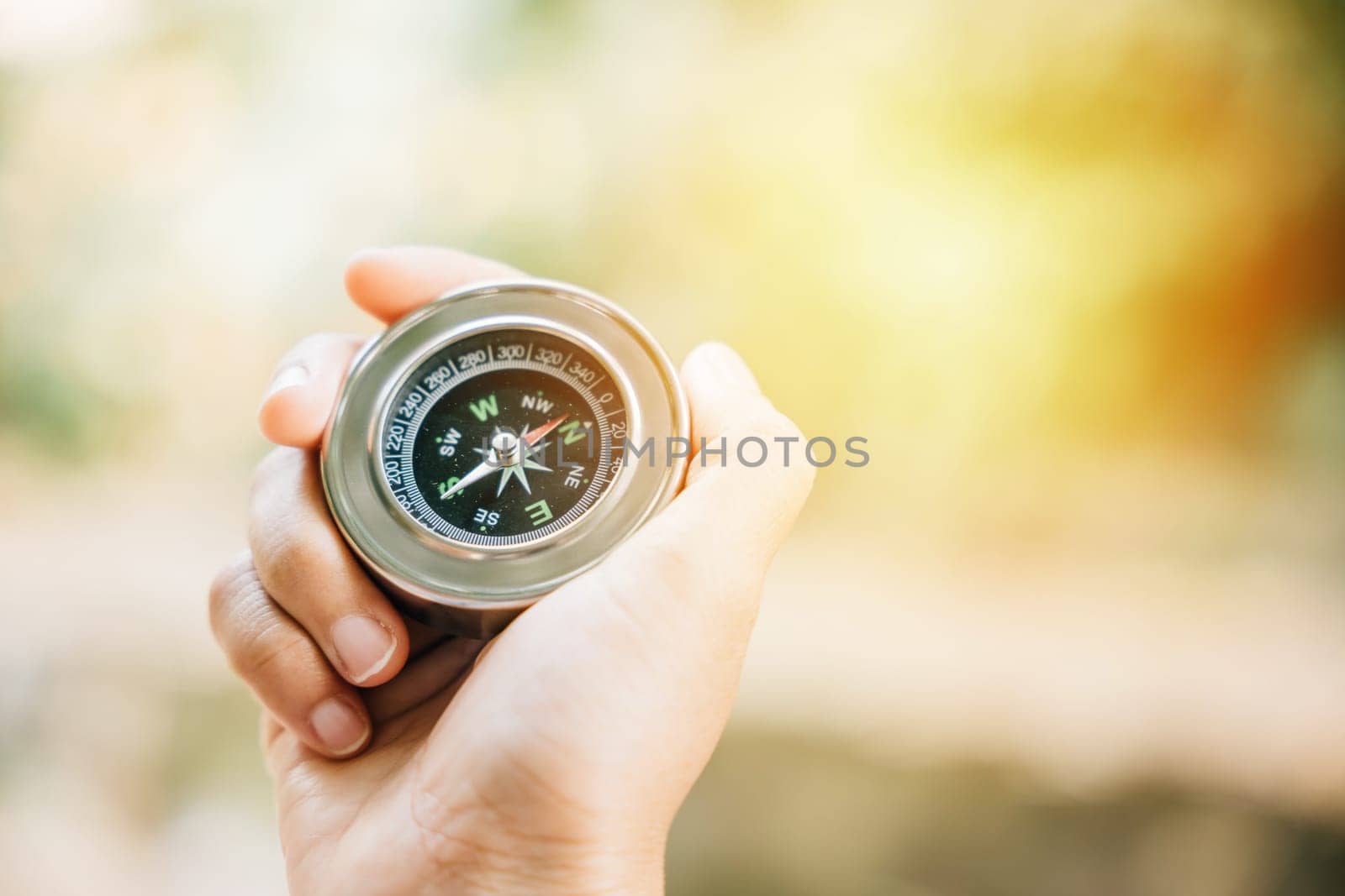 Traveler holds a compass in a park finding her way through the confusion. In her hand the compass represents guidance exploration and the journey to overcome defeat.