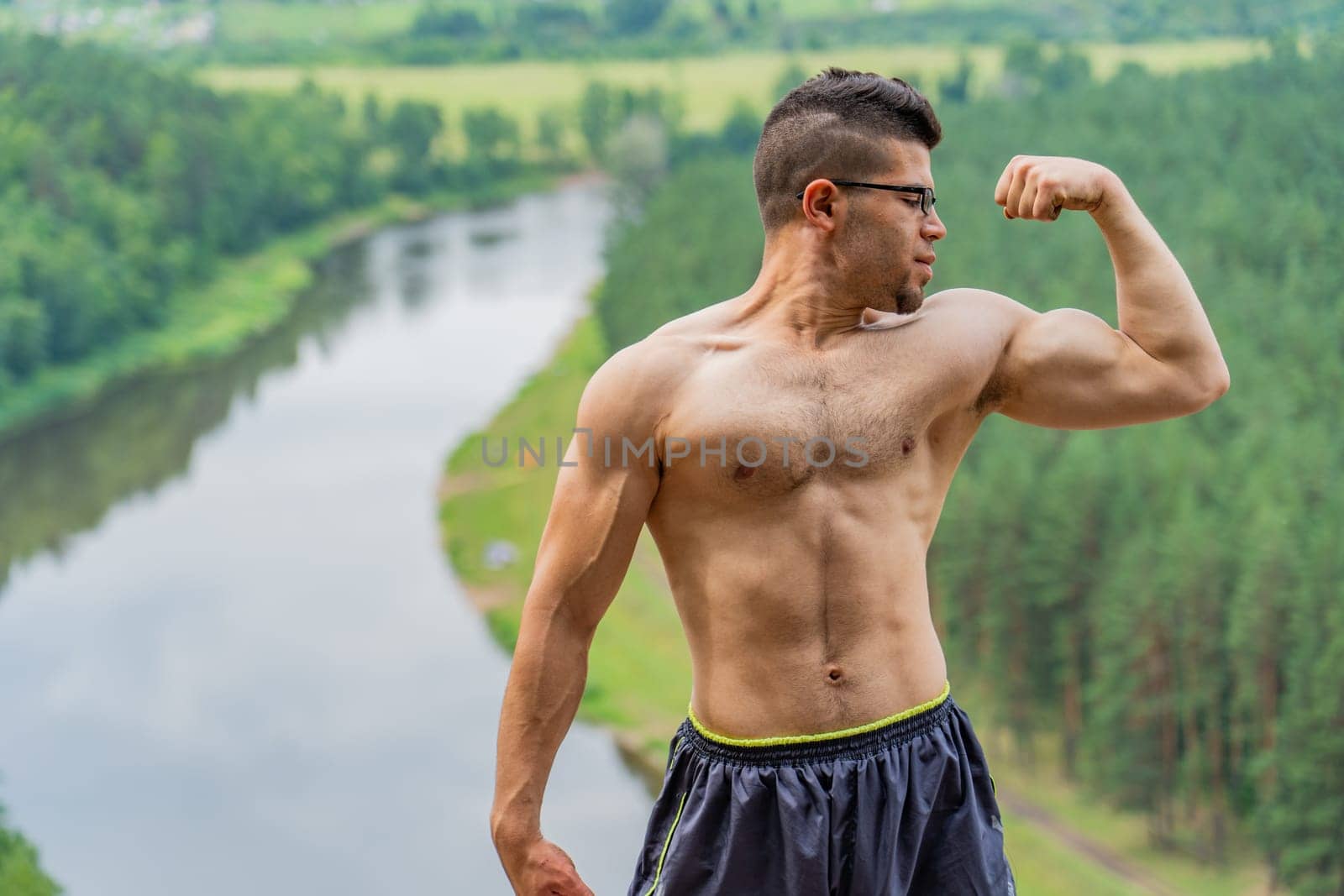 A young Jordanian guy demonstrates his muscles against the backdrop of beautiful nature