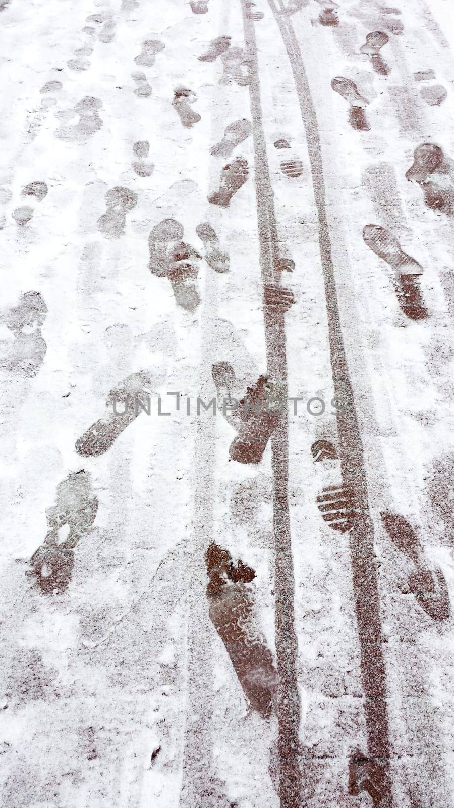 Footprints and tire tracks on a snowy surface, depicting winter travel and activity.