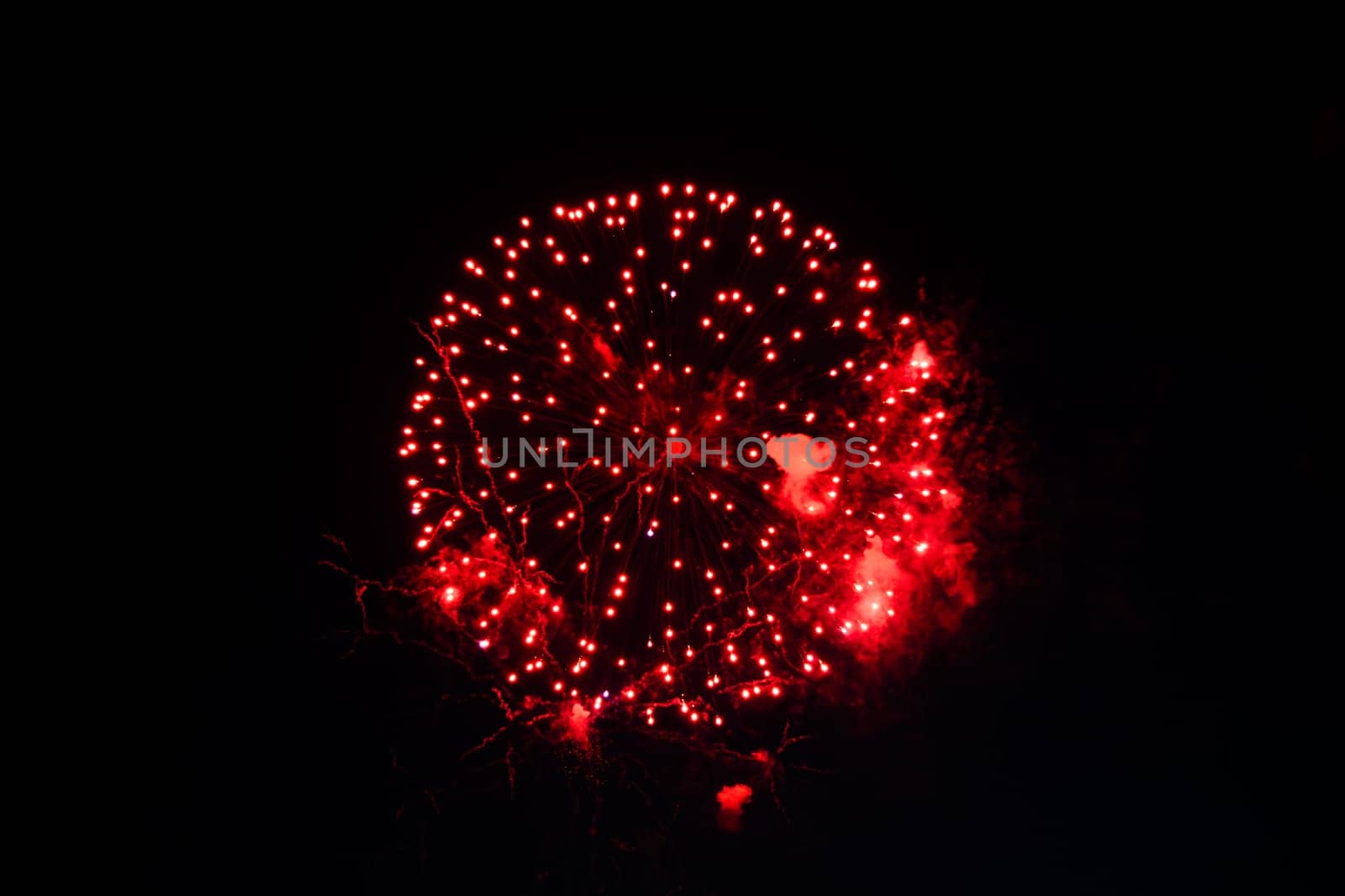 Red fireworks exploding in dark night sky, festive background concept