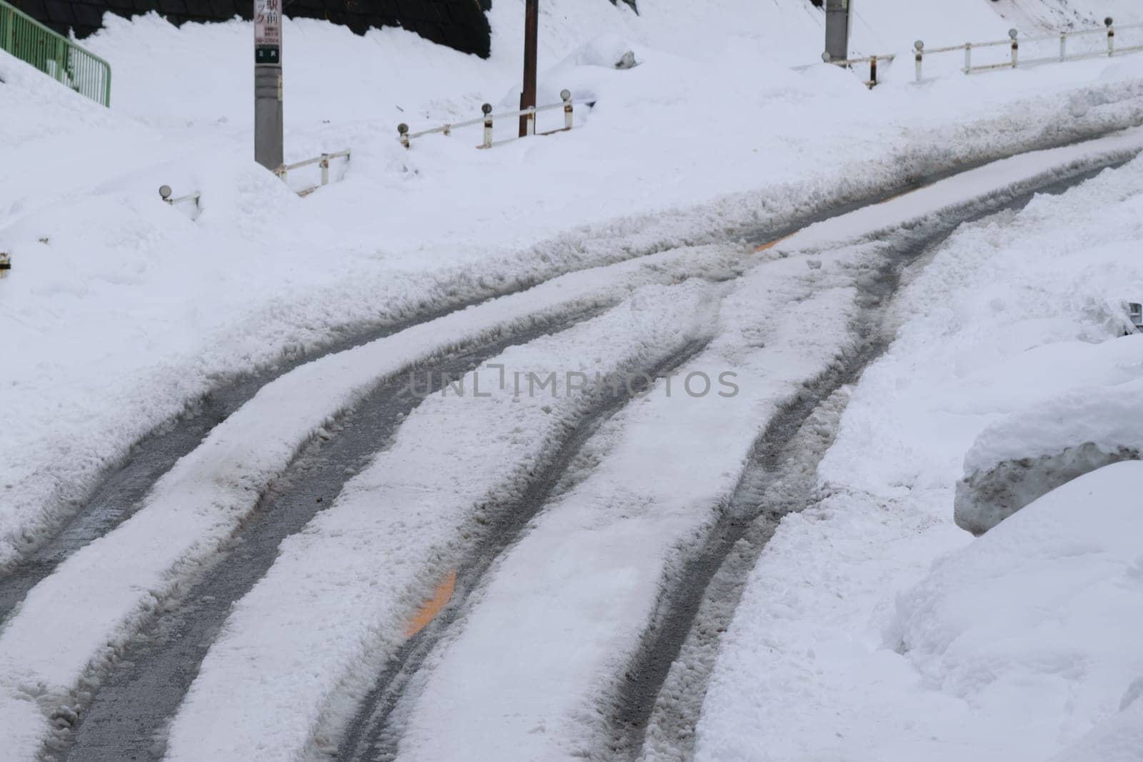 Winter scene with tire tracks on a snow-covered road, indicating recent vehicle passage.