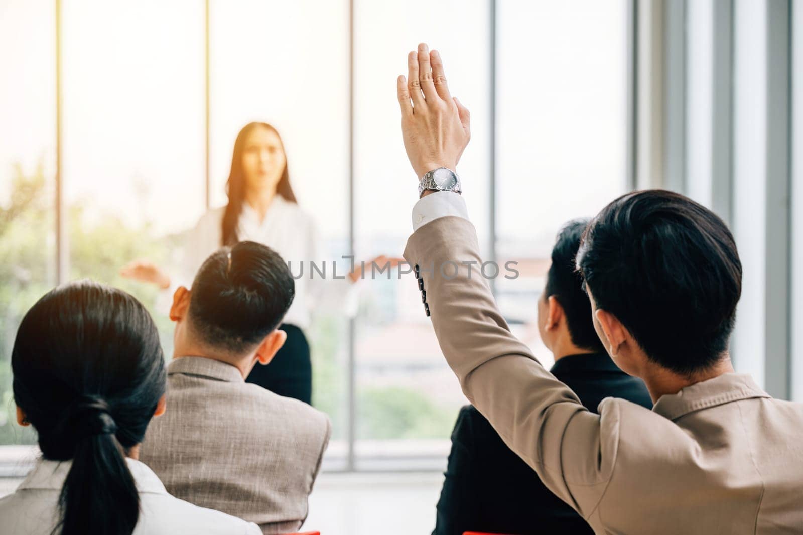 In a seminar classroom, a large group actively participates in the discussion, with raised hands indicating their engagement. The answers reside within this dynamic conference audience. by Sorapop