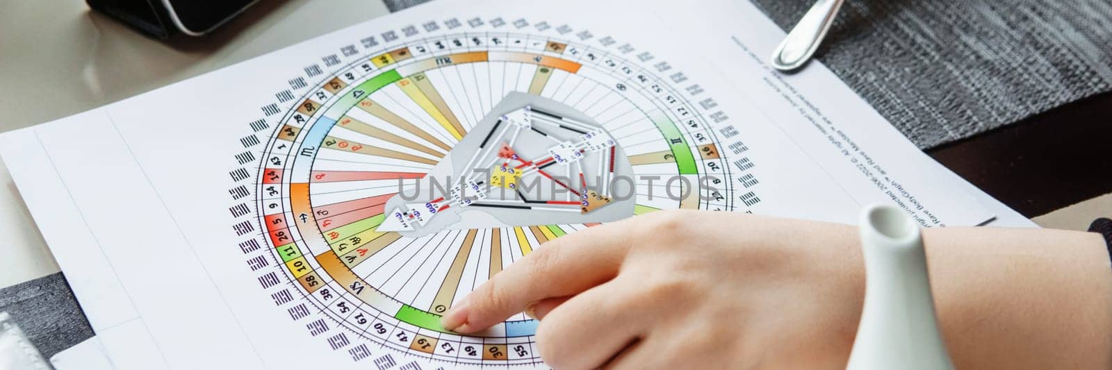 TVER, RUSSIA - FEBRUARY 12, 2023: A woman at the table is studying a rave mandala by human design. Rave mandala on the table close-up. The concept of esoteric teachings. by Annu1tochka