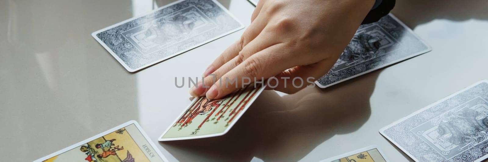 TVER, RUSSIA - FEBRUARY 11, 2023. Tarot cards, Tarot card divination, esoteric background. A woman makes a layout on the cards at the table. Divination, predictions on tarot cards