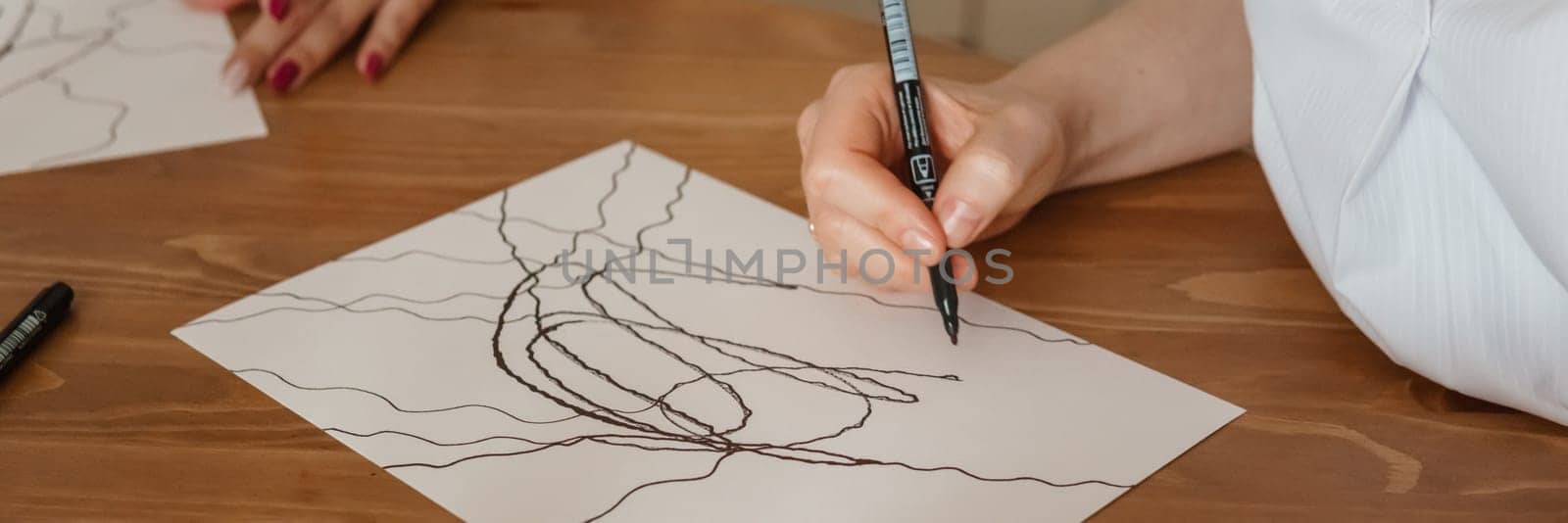 TVER, RUSSIA - FEBRUARY 25, 2023: Woman draws neurographics at table at a psychological session, neurographic pencil drawing to remove restrictions, art therapy.