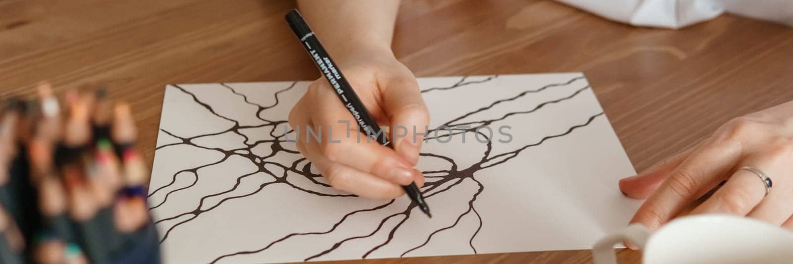 TVER, RUSSIA - FEBRUARY 25, 2023: Woman draws neurographics at table at a psychological session, neurographic pencil drawing to remove restrictions, art therapy.