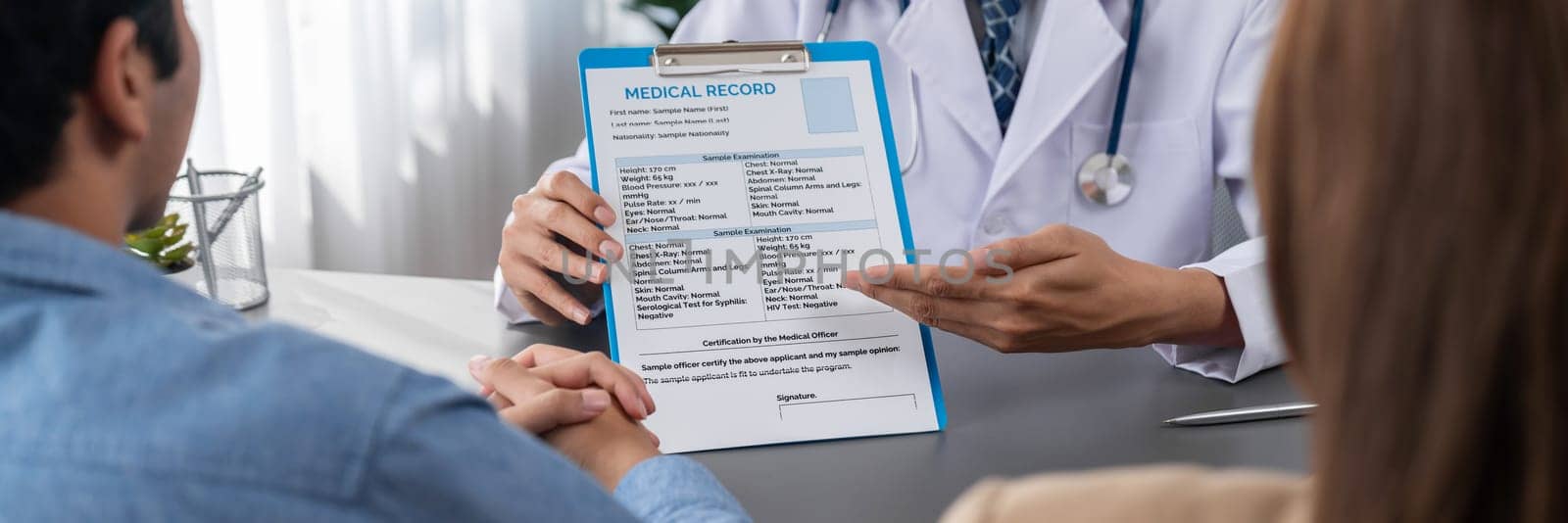 Doctor show medical diagnosis report and providing compassionate healthcare consultation to young couple patient in doctor clinic office. Doctor appointment and medical consult concept. Neoteric