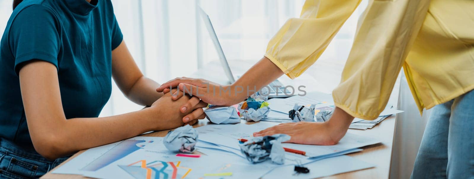 Panorama startup employee holding hand to stressed colleague due to failure, frustrated from no inspiration, lack of idea. Exhausted from overwhelm work and supportive coworker concept. Synergic