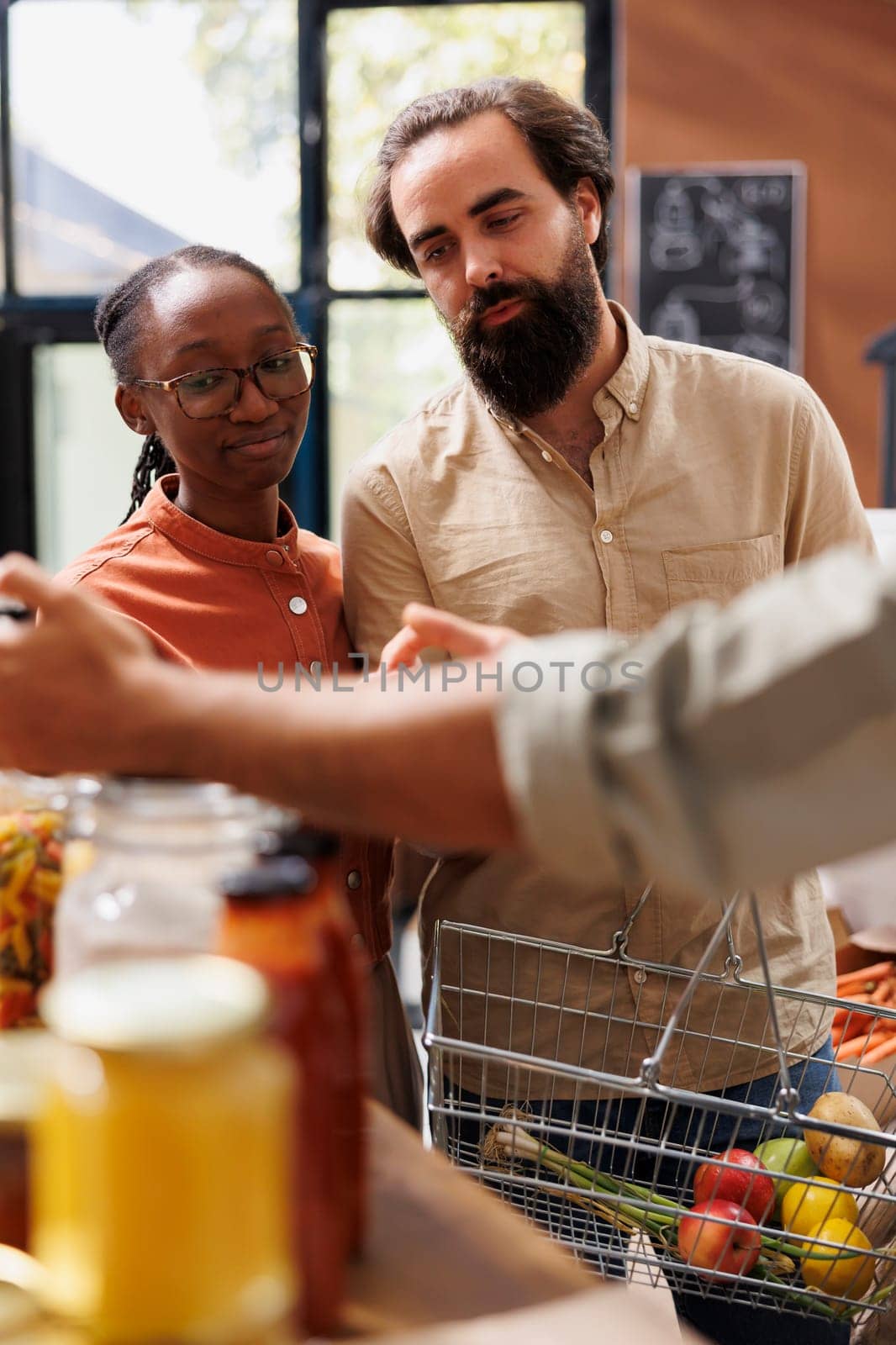 Close-up of caucasian boyfriend and African American girlfriend browsing through a section filled with fresh and natural merchandise. Interracial couple with a basket doing organic food shopping.