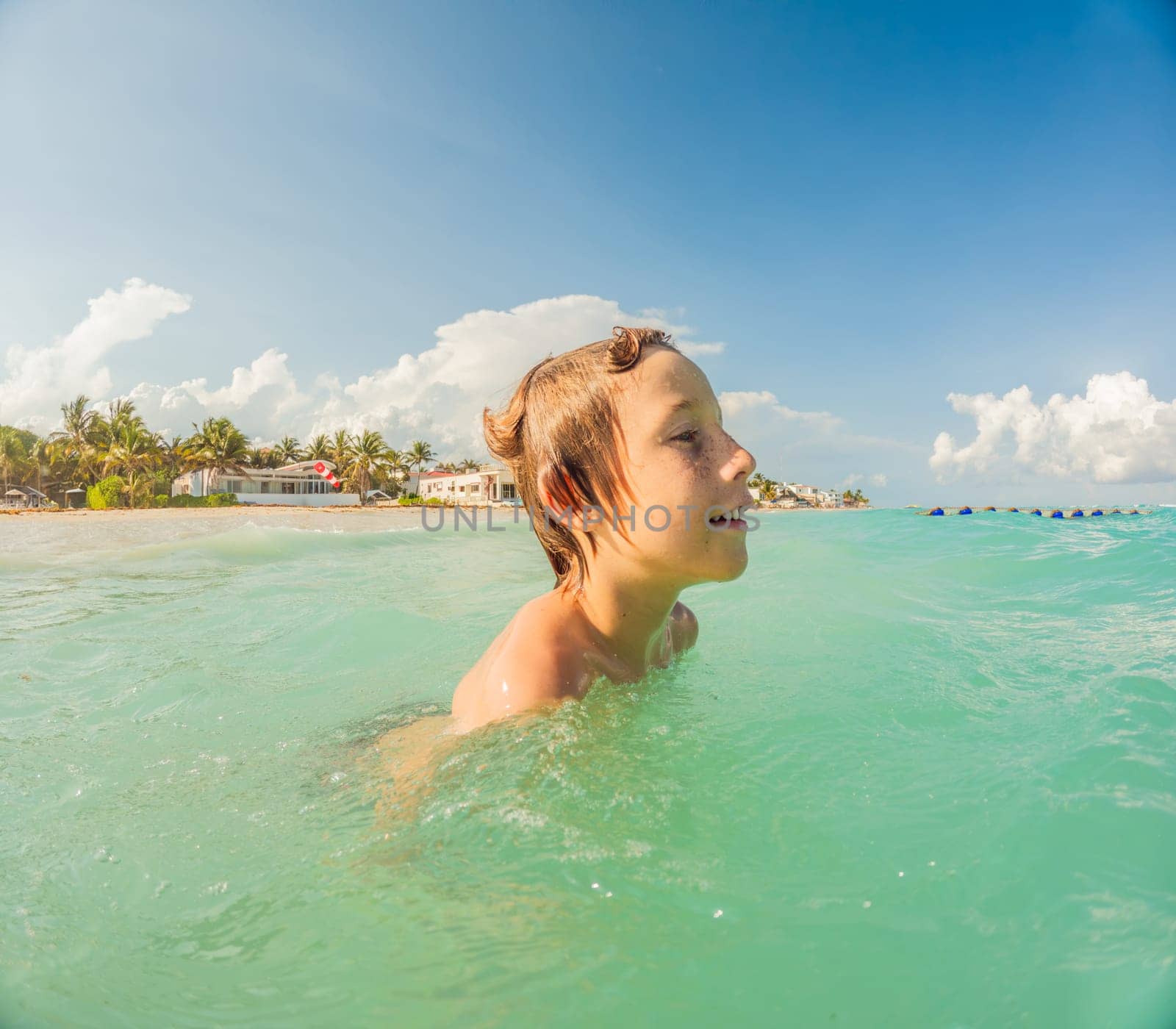 Joyful boy plays in the sea, creating playful splashes and enjoying the waves.