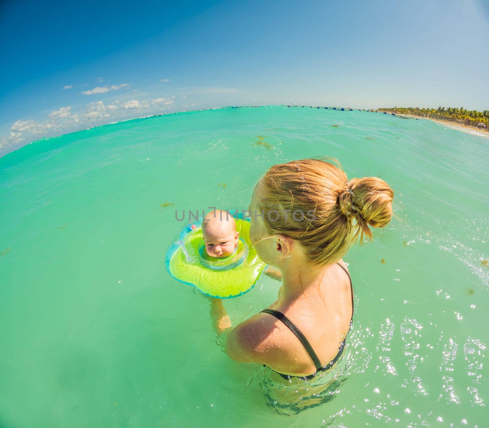 Adorable baby swims in an inflatable ring around his neck, enjoying the sea with his mom. by galitskaya