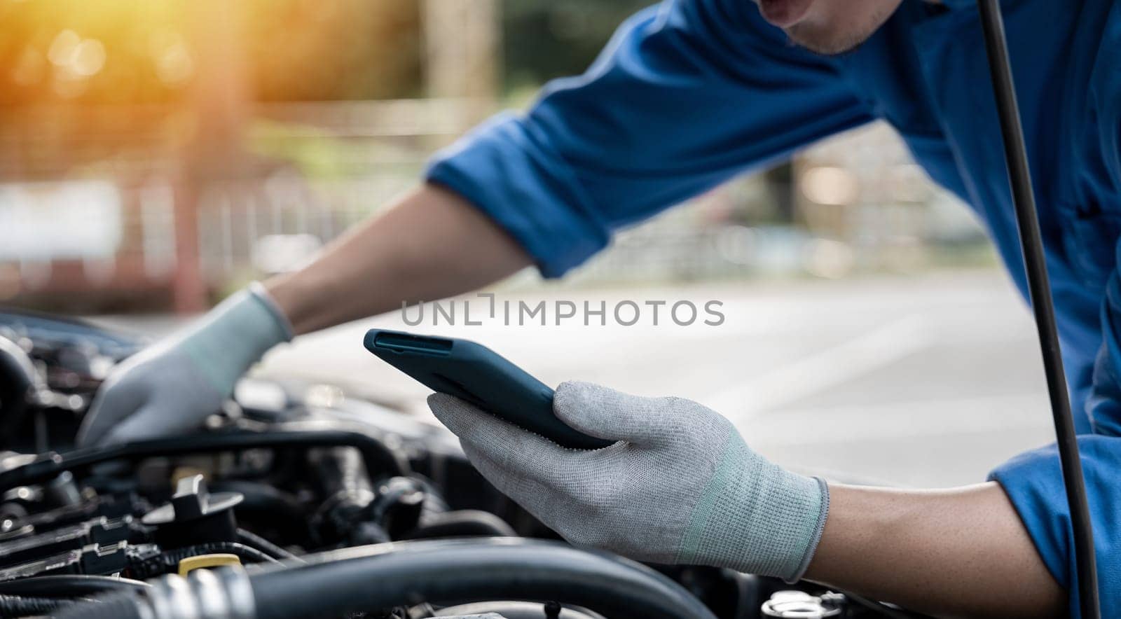 Skilled technician working with determination and pride at car repair station. Close-up shot of mechanic's hand turning wrench on car engine. Horizontal photo with workshop background.
