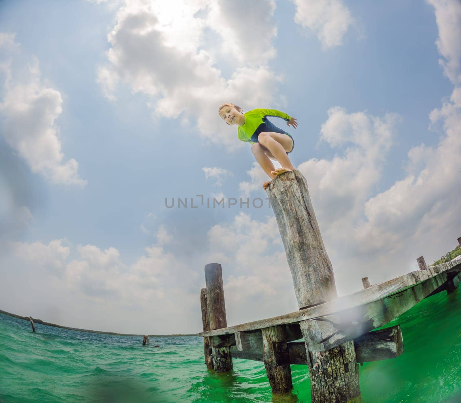 Joyful boy jumps into a turquoise lake in Mexico by galitskaya
