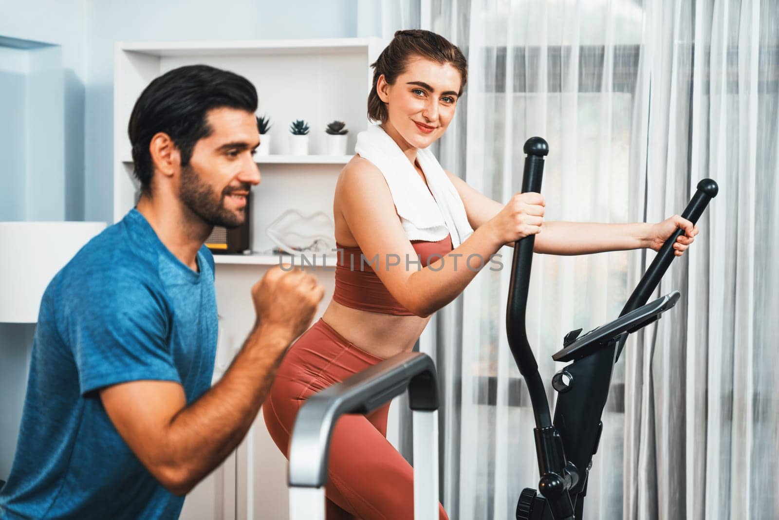 Athletic and sporty couple running on elliptical running machine at gaiety home. by biancoblue