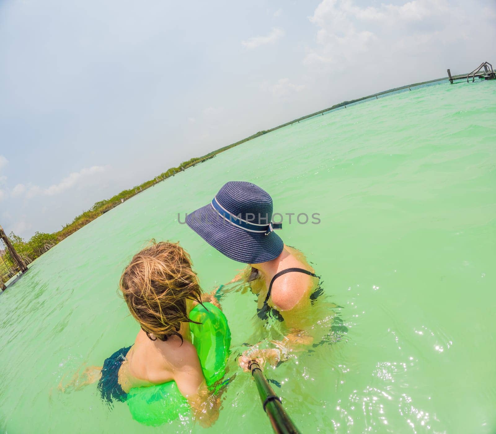 Mother and son enjoy a turquoise lake in Mexico by galitskaya