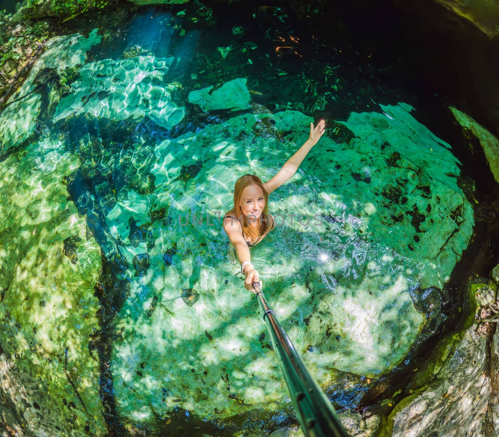 Woman immersed in the enchanting beauty of a Mexican cenote, surrounded by crystal-clear waters and captivating natural formations by galitskaya