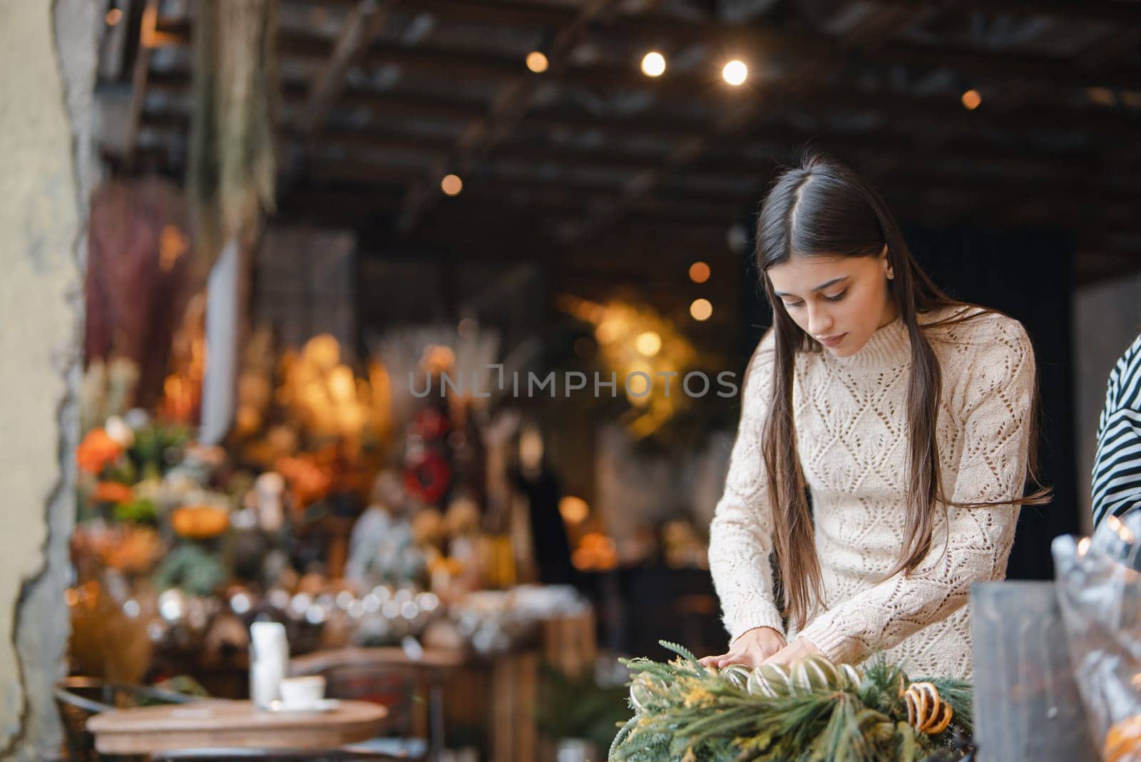 The final stages of crafting the Christmas wreath showcased on the flower shop counter. by teksomolika