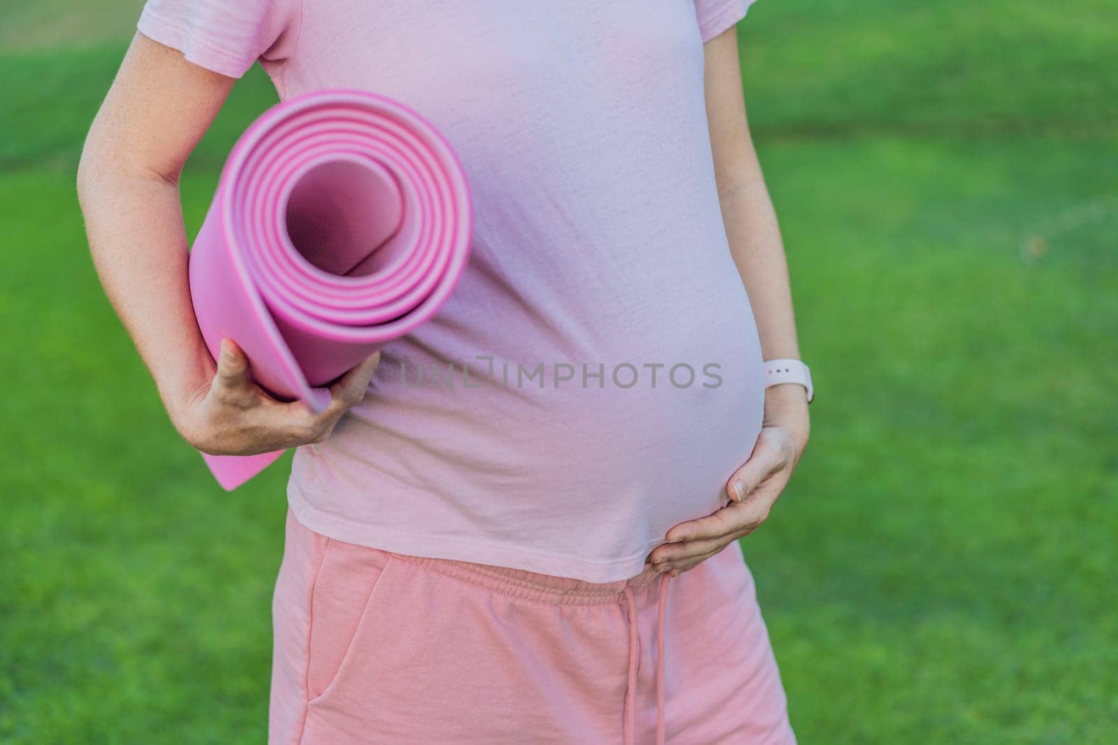 Energetic pregnant woman takes her workout outdoors, using an exercise mat for a refreshing and health-conscious outdoor exercise session by galitskaya