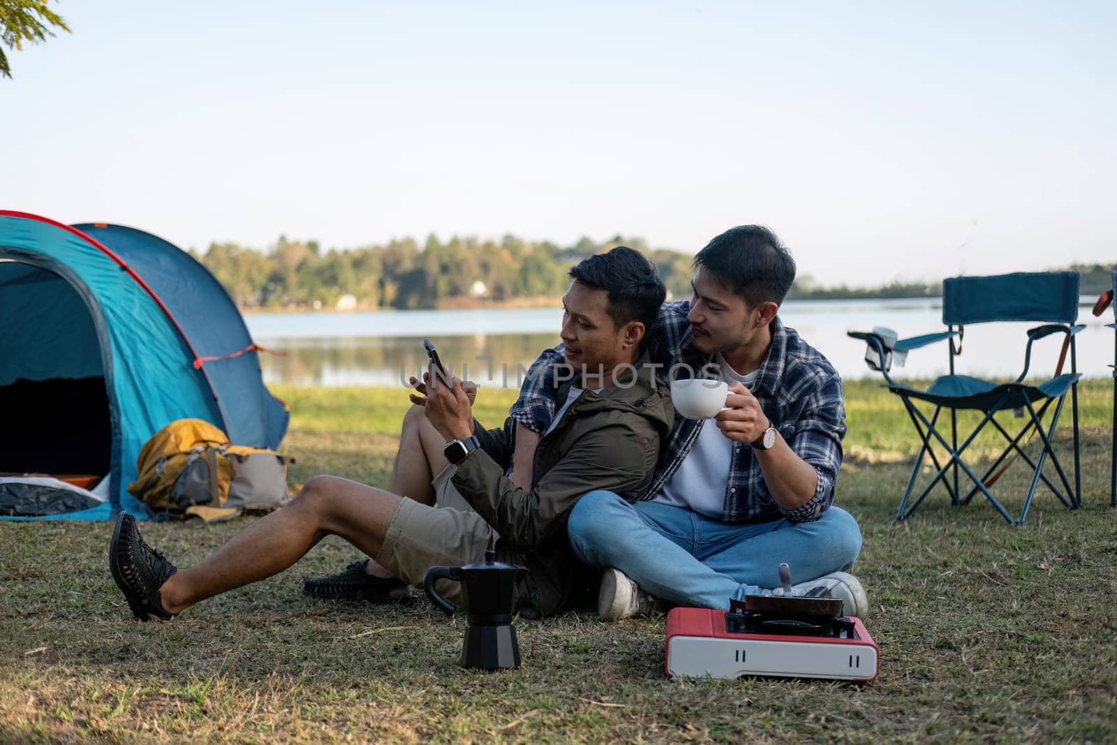 Happy Asian male gay couple on camping together in a forest. romantic vocation trip. lgbt concept by wichayada