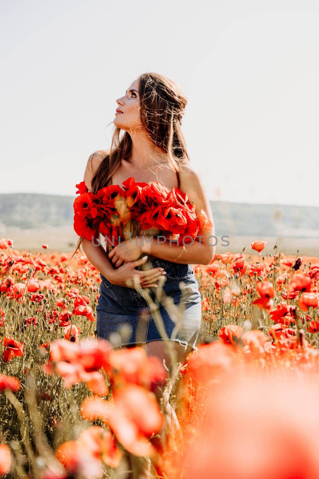 Woman poppies field. portrait of a happy woman with long hair in a poppy field and enjoying the beauty of nature in a warm summer day