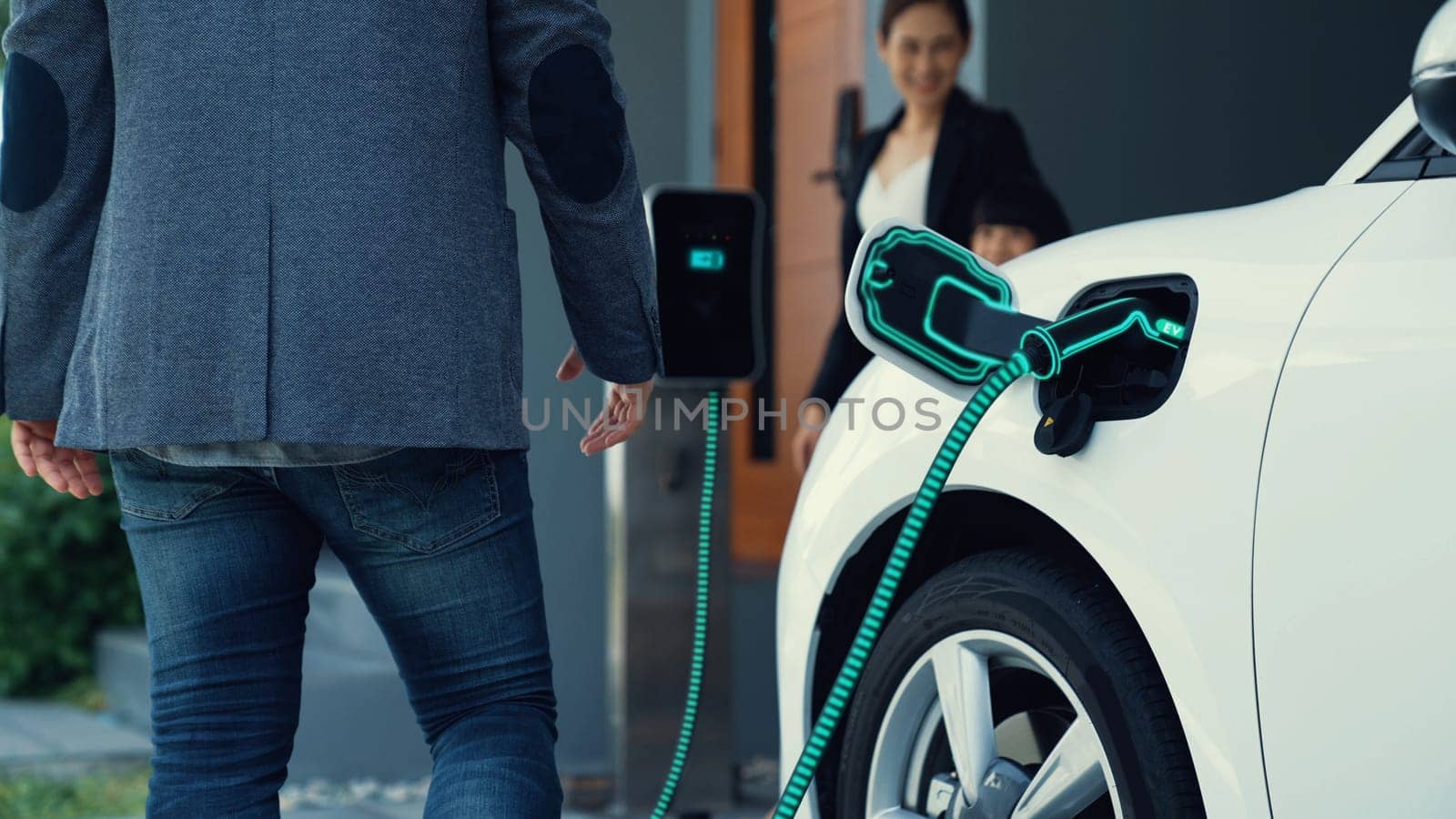 Modern family couple recharge electric car, EV charger from home charging station plugged in EV car in house garage. Smart and futuristic home energy infrastructure. Peruse