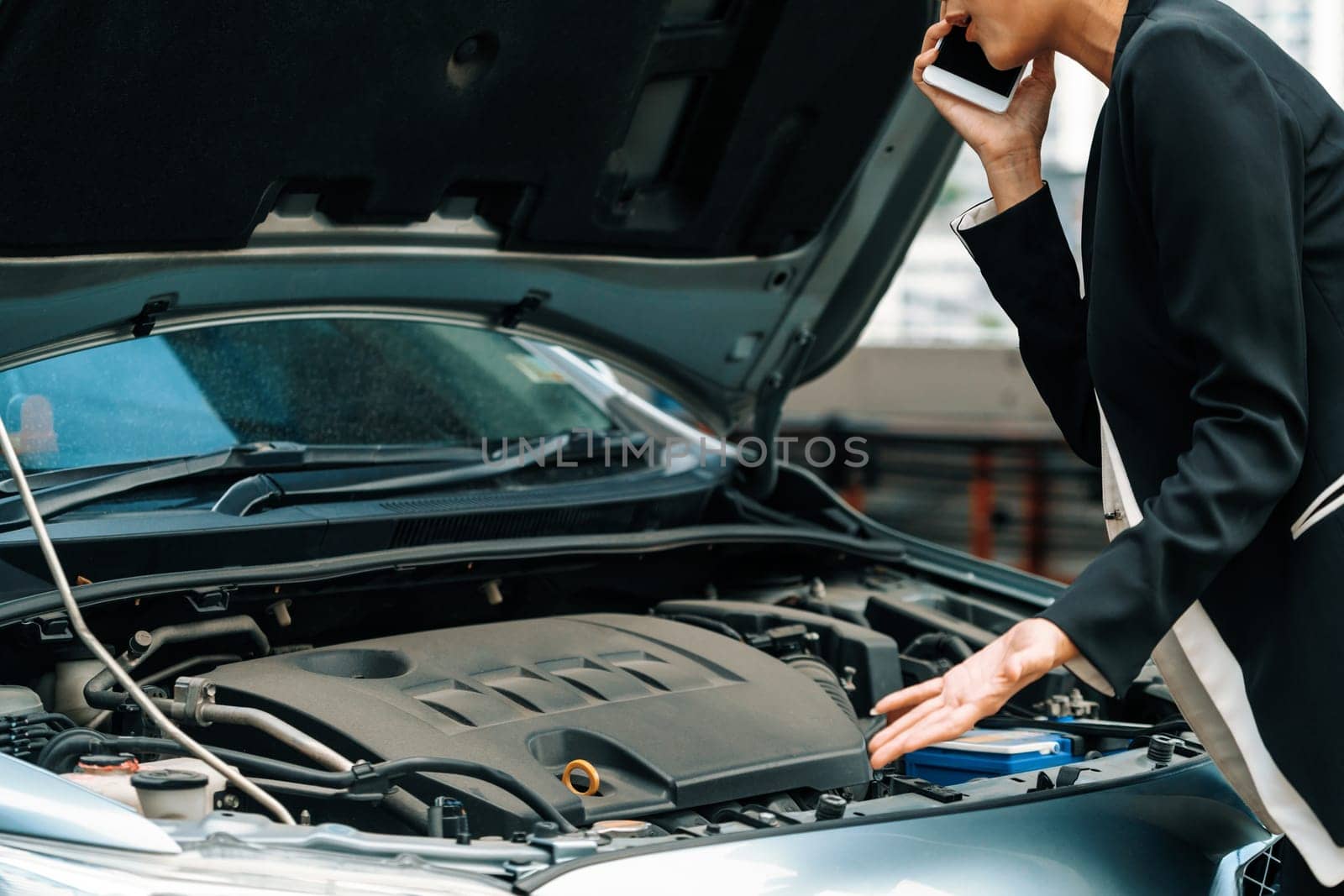 Young businesswoman whose car breakdown uses mobile phone to call for roadside assistance service. Travel and transportation vehicle problem. uds