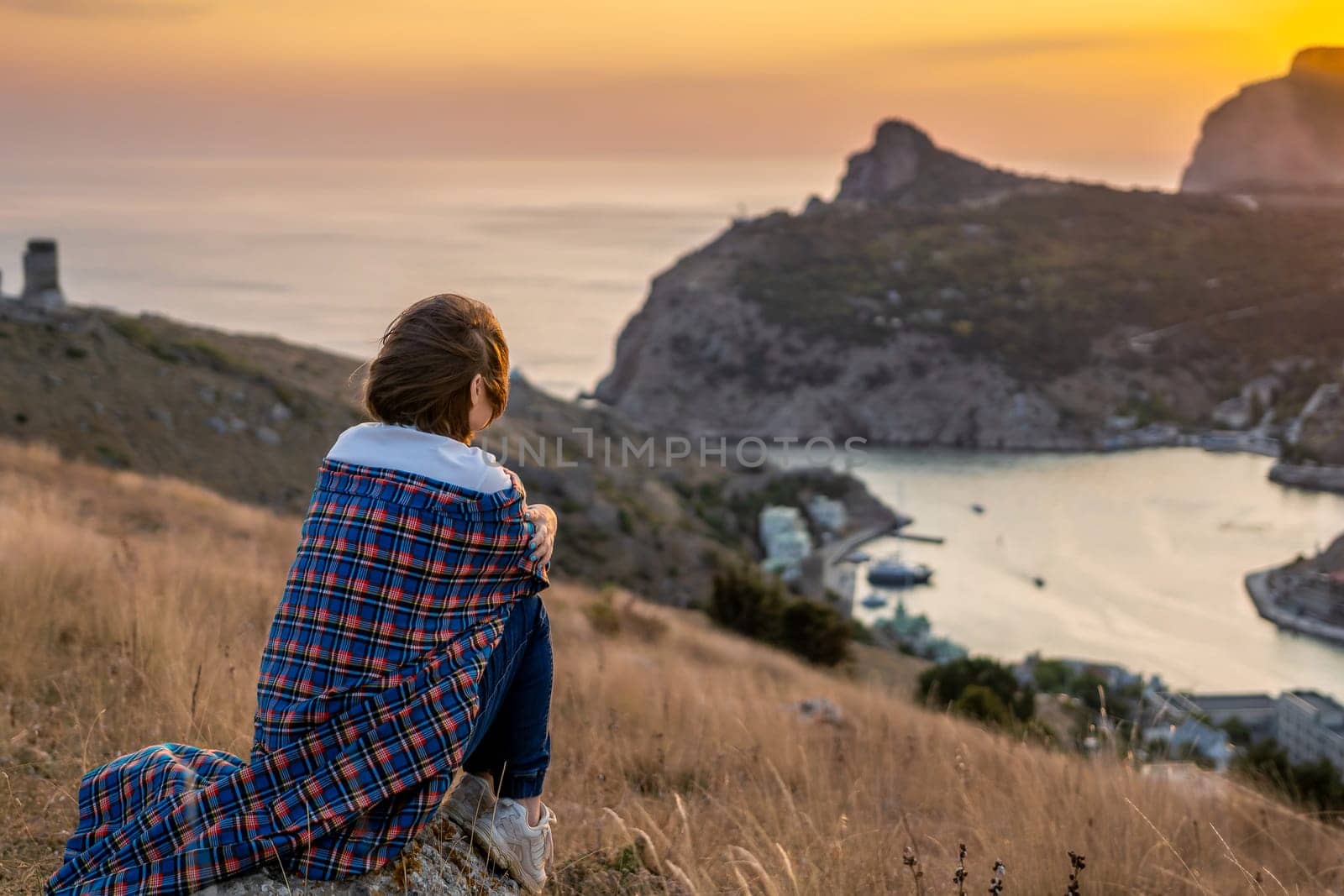 Happy woman on sunset in mountains. Woman siting with her back on the sunset in nature in summer. Silhouette