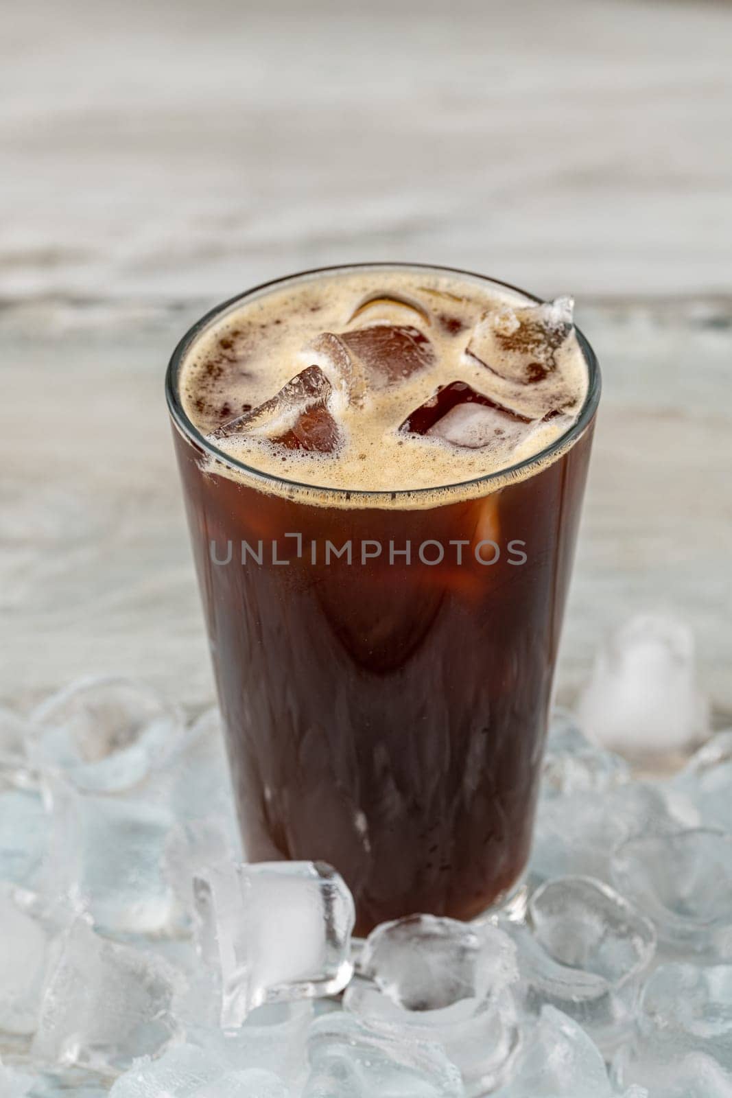 A cup of Iced Americano Coffee with ice cubes placed on a wooden table in a coffee shop. Top view of a glass of coffee.