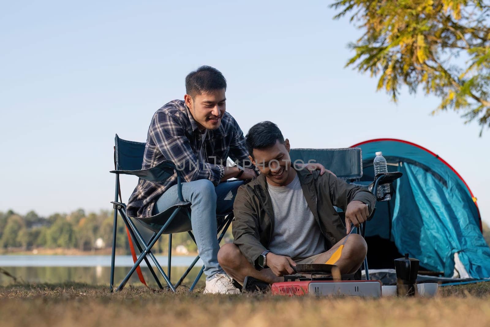 Happy Asian male gay couple on camping together in a forest. romantic vocation trip. lgbt concept by wichayada