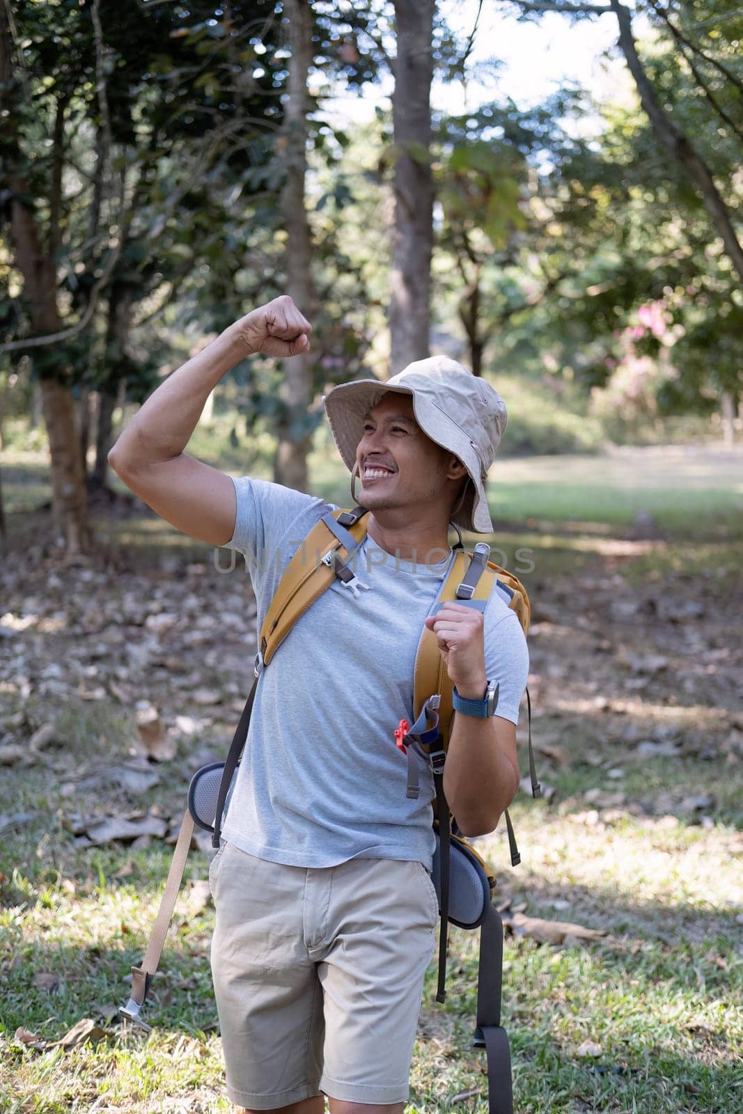 Portrait of a happy smiling Asian tourist, 30-35 years old, backpacking in a national park. asian male tourist enjoying his hiking trip Nature activities, holidays, outdoor hobbies. by wichayada