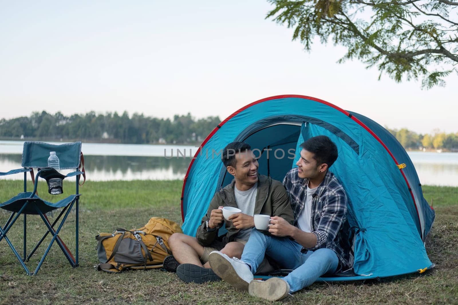 Happy Asian male gay couple on camping together in a forest. romantic vocation trip. lgbt concept by wichayada