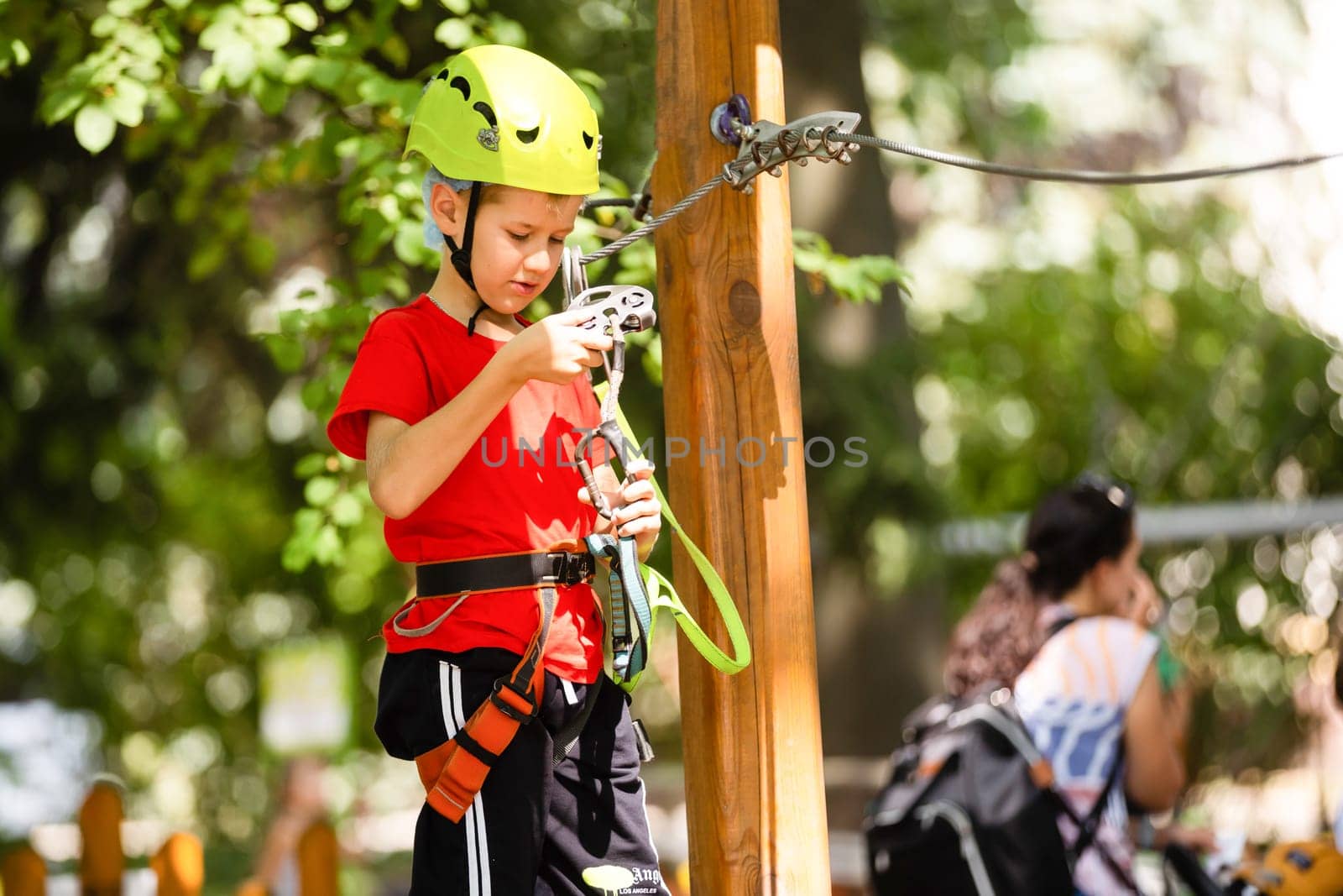 Cute school boy enjoying a sunny day in a climbing adventure activity park by Andelov13
