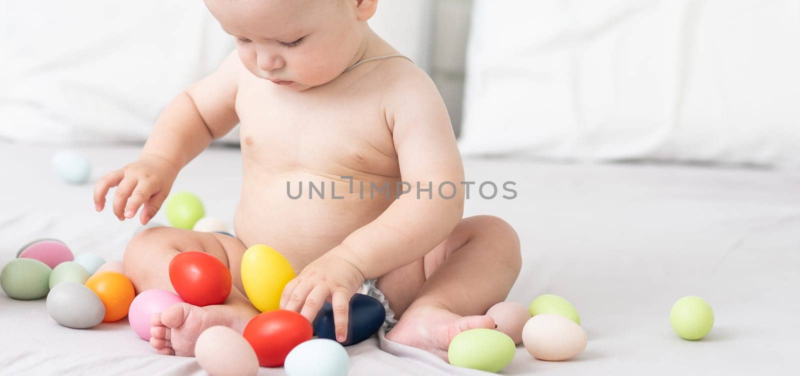 Portrait of a cute baby dressed in Easter bunny ears with a basket full of eggs by Andelov13