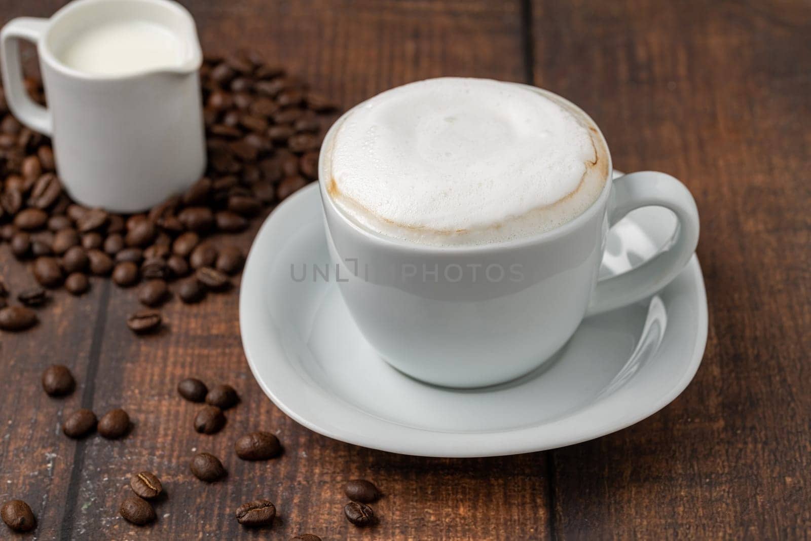 Cappuccino coffee in a white porcelain cup on a wooden table by Sonat