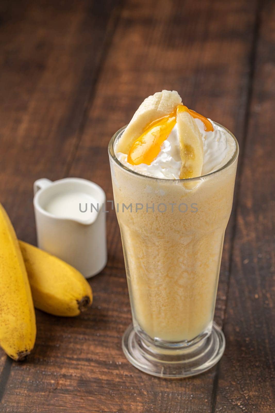Banana smoothie in glass cup on wooden table by Sonat