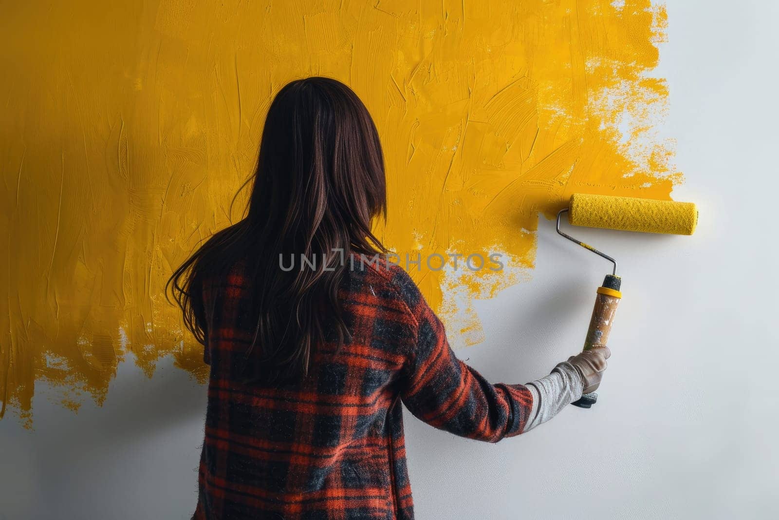 The girl paints with bright yellow paint on the surface of the wall. by Yurich32
