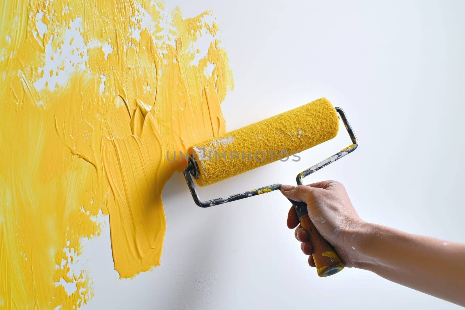 The process of painting a wall bright yellow with a paint roller.